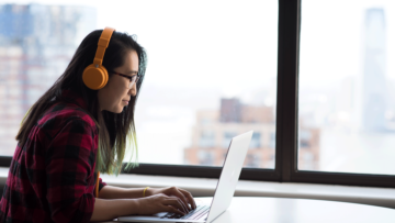 Woman at computer, wearing orange headphones