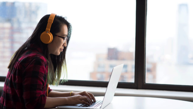 Woman at computer, wearing orange headphones