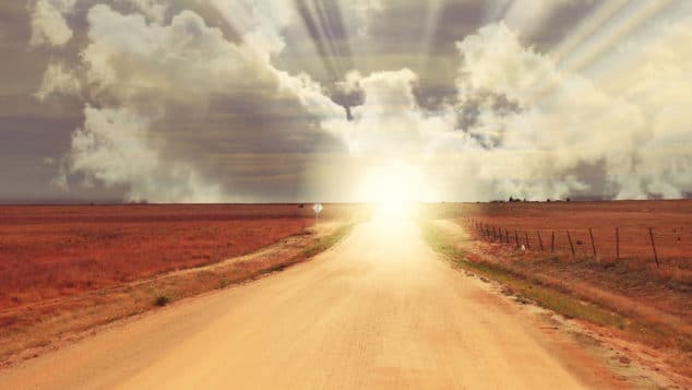 A dirt path leads toward a sunny horizon.