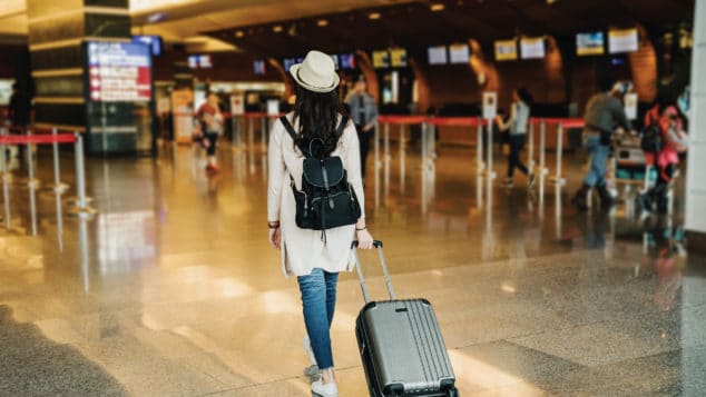 A woman carries a suitcase through the airport.