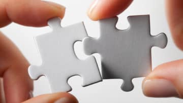 Two jigsaw pieces are being fit together.