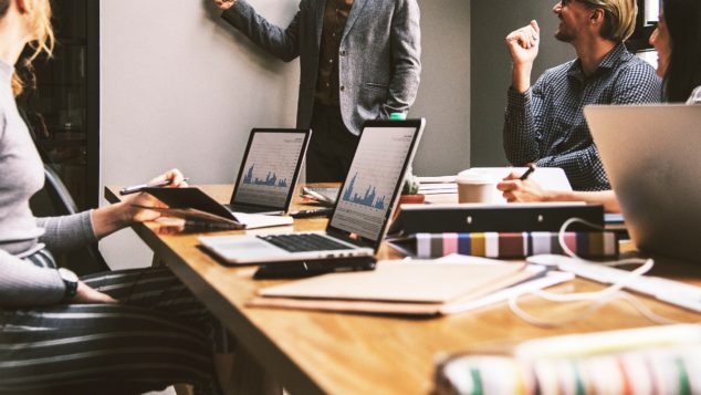 Employees look over figures at a team meeting.