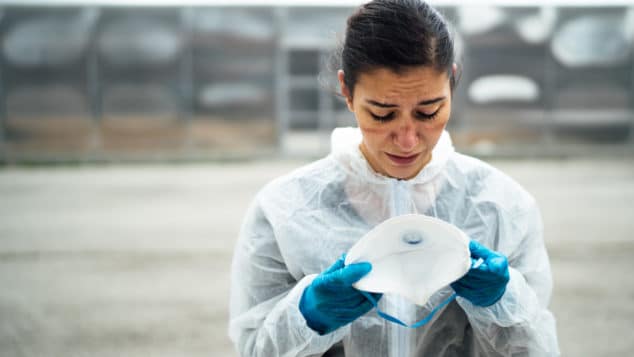 Female healthcare worker removing mask and looking dismayed