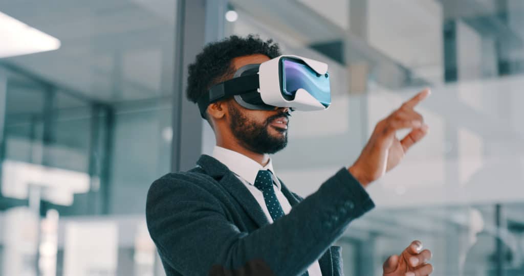 Shot of a young businessman using a virtual reality headset in a modern office, metaverse
