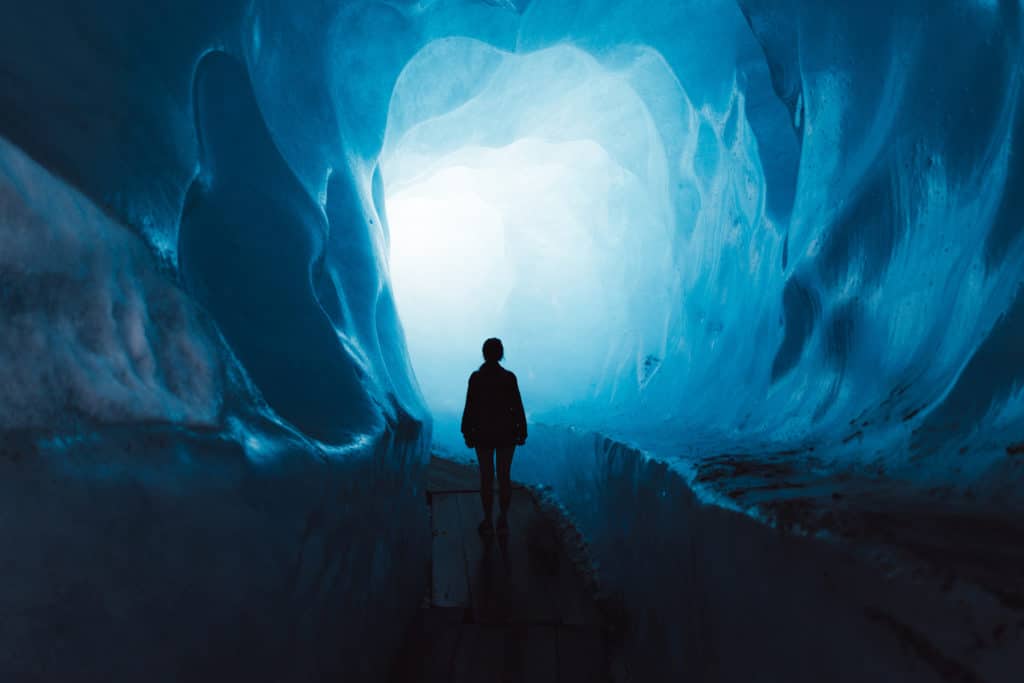 Woman Exploring The World Of A Big Glacier Inside The Ice Cave In Switzerland